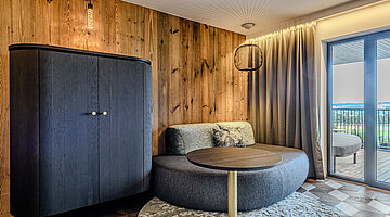 Wohnbereich der Juniorsuite Kuschelnest Gemütlicher Wohnbereich der Juniorsuite Kuschelnest im Hotel Winzer mit runder Sitzecke, Naturholzwand und Balkon