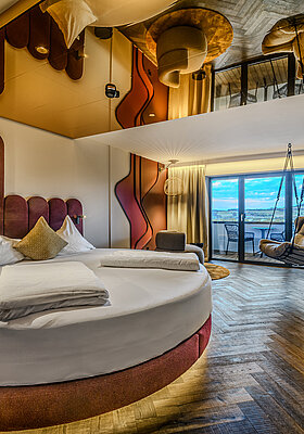 Sleeping Area with Round Bed and Hanging Chair Secret Love Suite at Hotel Winzer with a round double bed, hanging chair, cosy living area and balcony