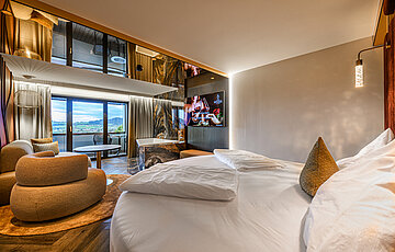 Sleeping area in the Kuscheltraum Junior Suite at Hotel Winzer with double bed, cosy seating area, bathtub and balcony with countryside views