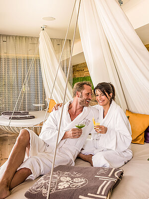 A couple relaxing in floating cosy nests at the Hotel Winze