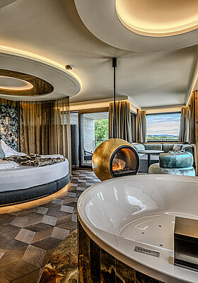 Hideaway Suite with Whirlpool Bath and Fireplace Hideaway Suite at Hotel Winzer with private whirlpool bath, round double bed, freestanding fireplace and a spacious living area for two
