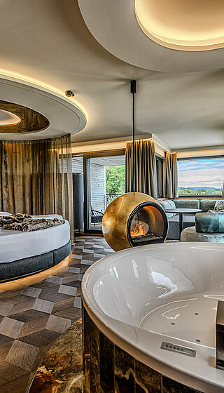 Hideaway Suite with Whirlpool Bath and Fireplace Hideaway Suite at Hotel Winzer with private whirlpool bath, round double bed, freestanding fireplace and a spacious living area for two