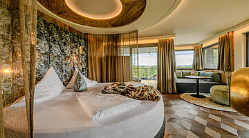 Sleeping Area in the Hideaway Suite Sleeping area in the Hideaway Suite at Hotel Winzer with a round double bed, cosy living area, balcony and freestanding fireplace