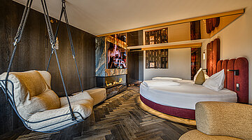 Sleeping Area with Fireplace Sleeping area in the Secret Love Suite at Hotel Winzer with a round double bed, hanging chair and contemporary fireplace