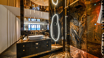 Bathroom in the Kuscheltraum Junior Suite Bathroom in the Kuscheltraum Junior Suite at Hotel Winzer with natural stone, an elegant vanity, illuminated mirror and shower