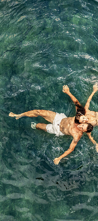A couple in the water of the natural pool at the Winzer Wellness Hotel