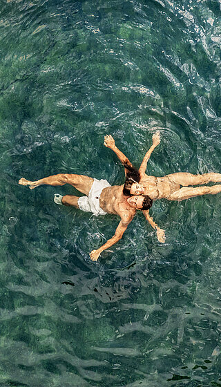 A couple in the water of the natural pool at the Winzer Wellness Hotel
