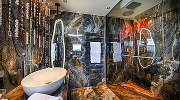 Bathroom in the Hideaway Suite Bathroom in the Hideaway Suite at Hotel Winzer with natural stone, an elegant vanity, illuminated mirror and spacious glass-enclosed shower
